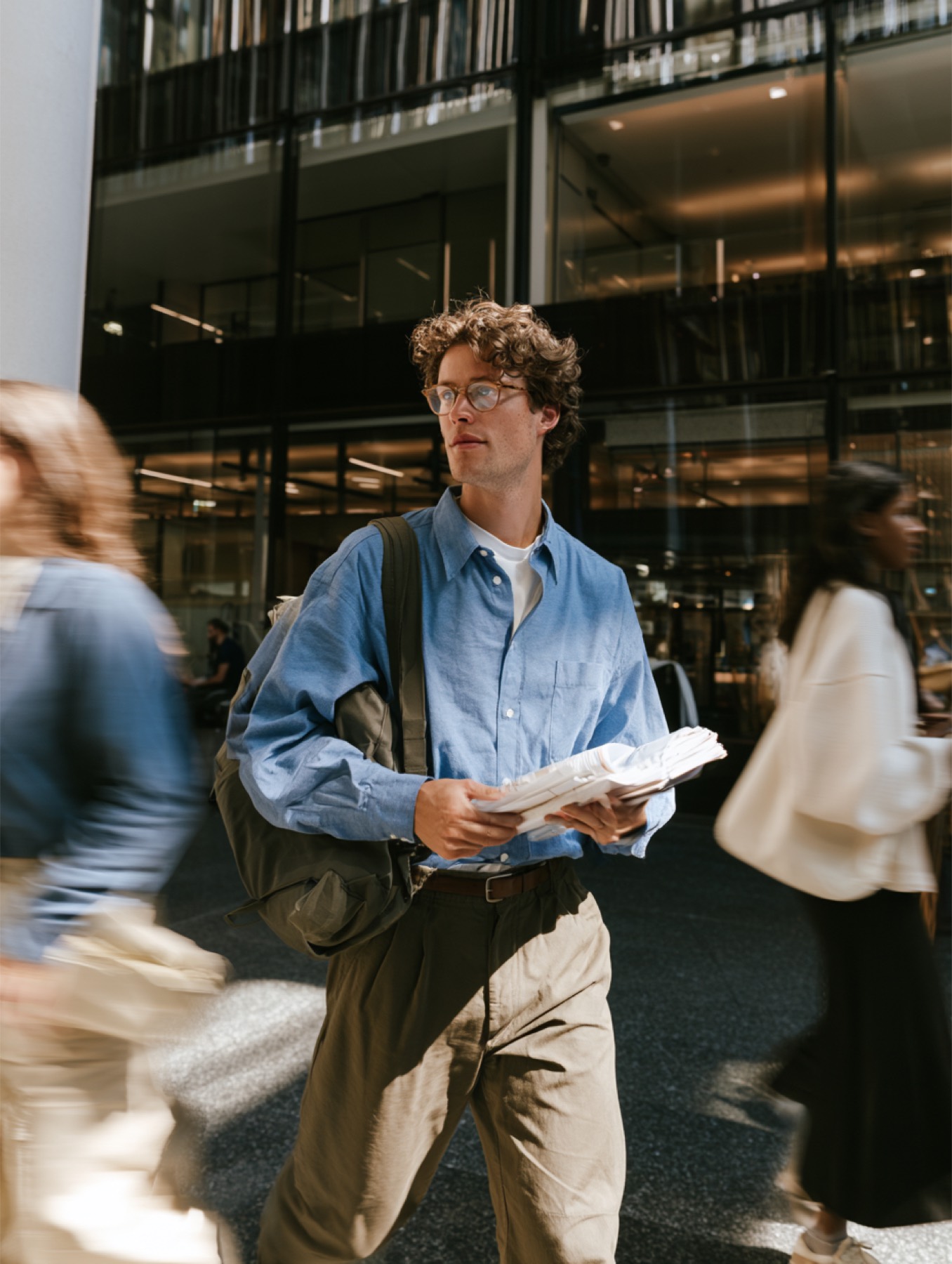 A man walking out of a building with papers in hand
